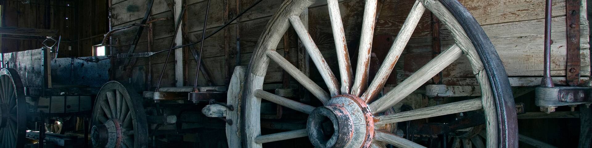A wooden wagon with large, rusted wheels in a barn.