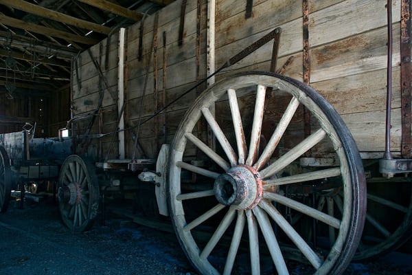 Une charrette en bois aux grandes roues rouillées, dans une grange.