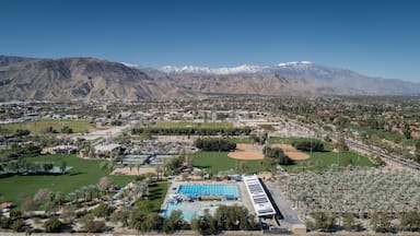 An aerial view of a town with a large swimming pool, baseball fields, and mountains in the background.