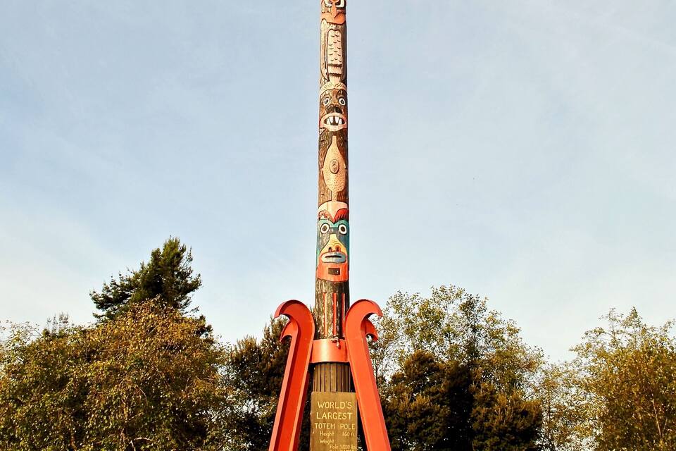 Un grand totem, richement sculpté, avec une plaque commémorative à sa base.
