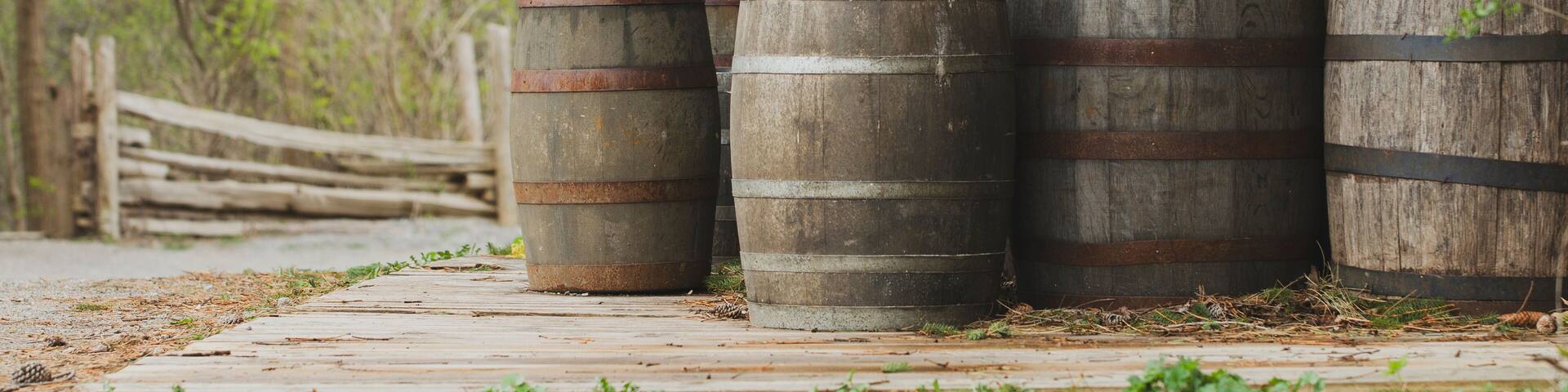 Group of rustic wooden barrels on a wooden deck with natural forest background.