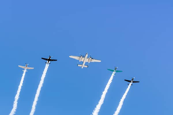 Historical airplanes flying in formation, leaving behind a white smoke trail; California