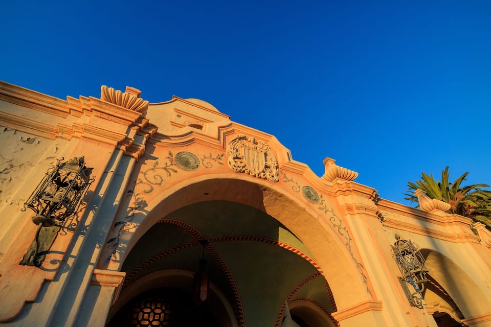An ornate archway with intricate carvings and a clear blue sky above.
