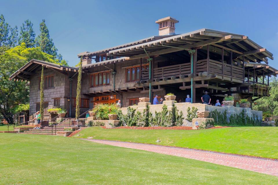 A large, rustic house with a covered porch and a stone staircase leading up to it.