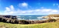 Un paysage côtier avec des falaises, des vagues de l’océan et un ciel dégagé.