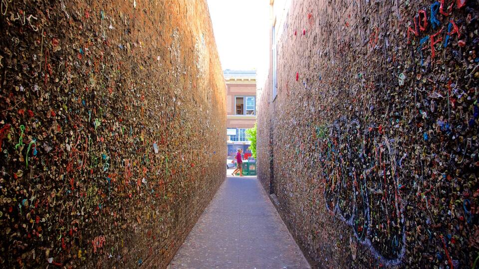 A narrow alley flanked by walls covered in colorful ribbons and notes.