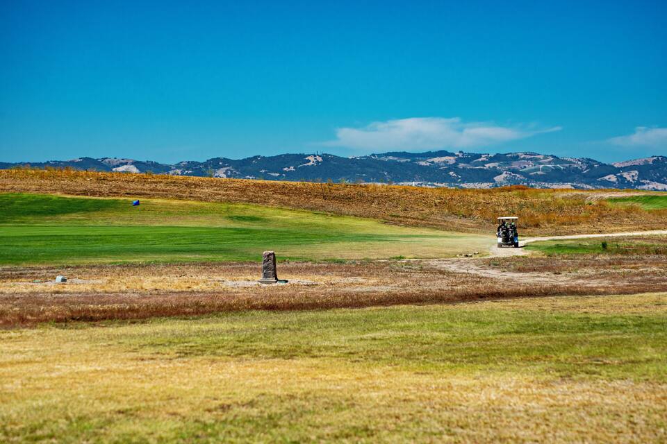 A golf course with a clear sky, green fairways, and distant mountains.