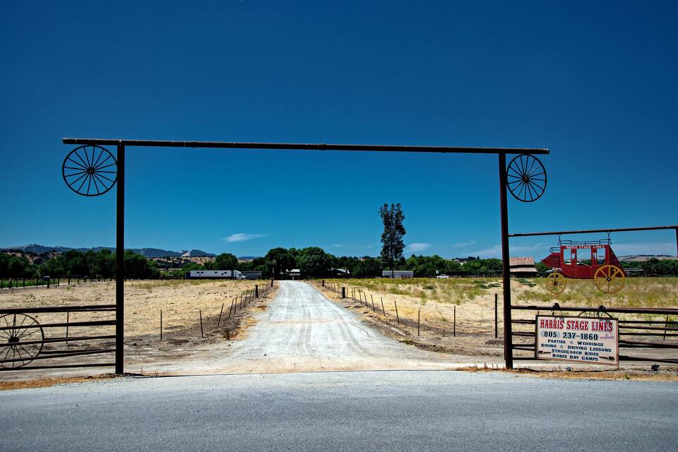 Una strada sterrata che conduce a un cancello con un cartello per Harris Stage Lines.
