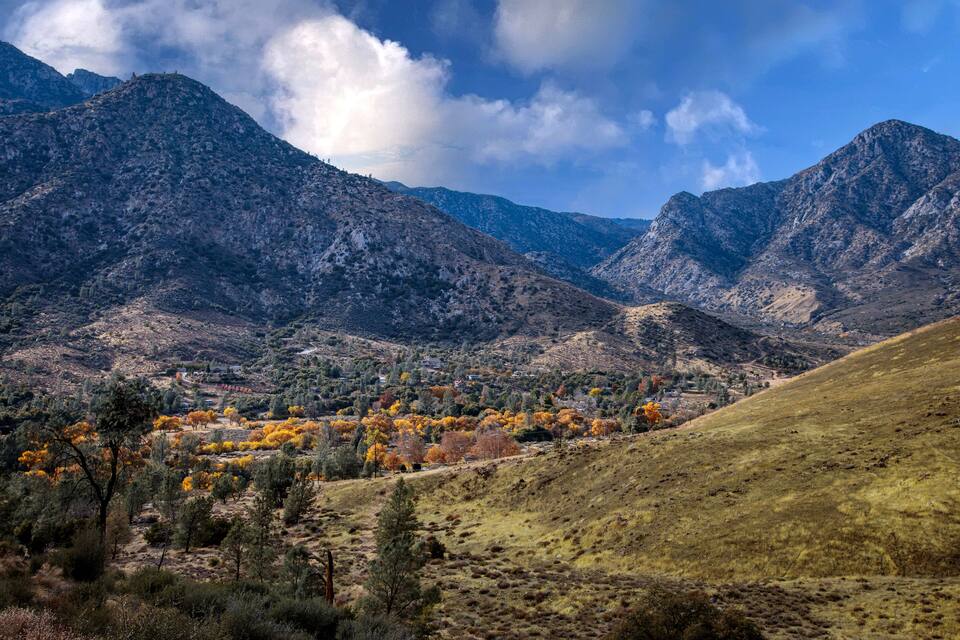 Un paysage montagneux, avec des arbres aux couleurs automnales et une vallée.