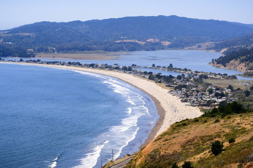 A coastal town with a beach, ocean, and hills.