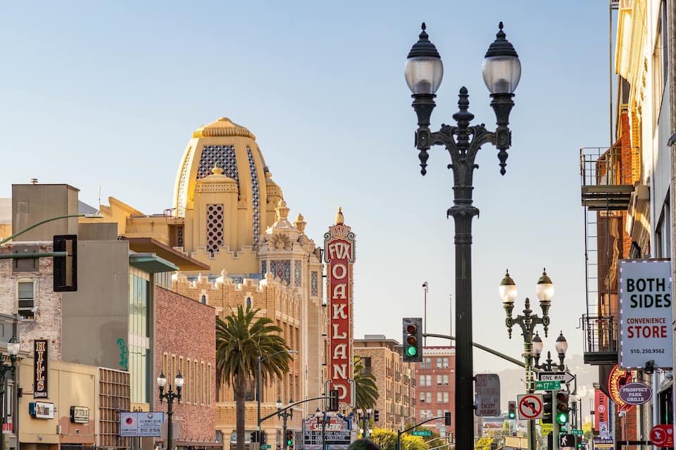 A city street with a prominent building with a dome and a sign that reads "FOX OAKLAND".