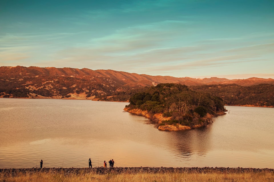 A lake with a small island in the center surrounded by mountains.