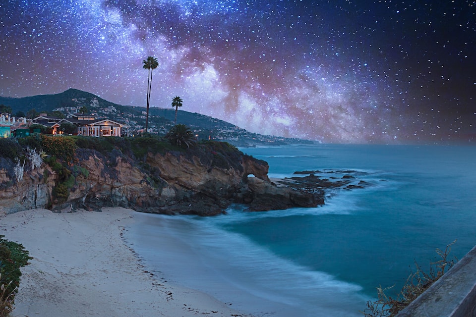 A coastal landscape with a beach, a mountain, and a house overlooking the ocean.