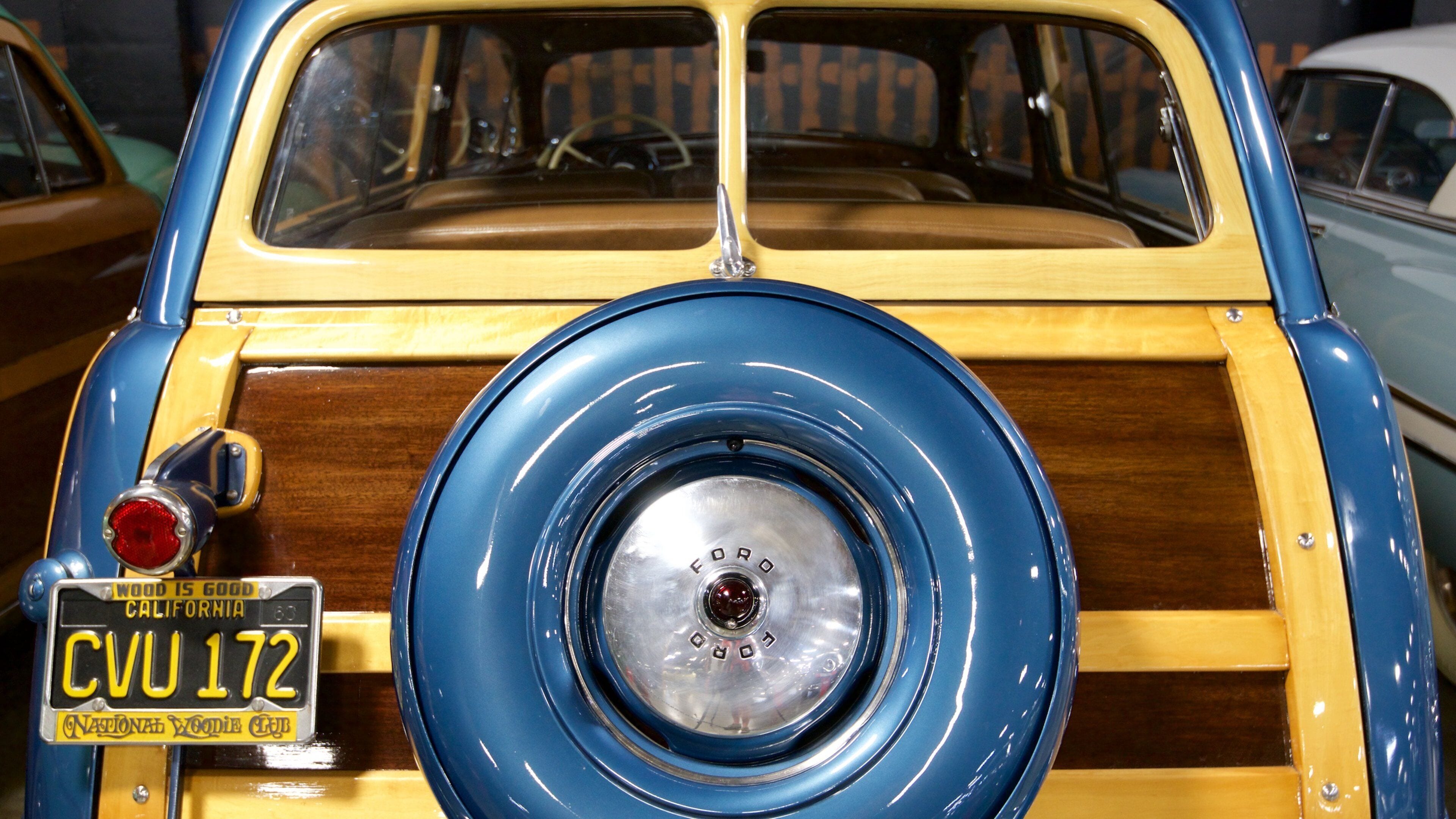 Un coche antiguo azul y amarillo con interior de madera y una placa de matrícula de California.