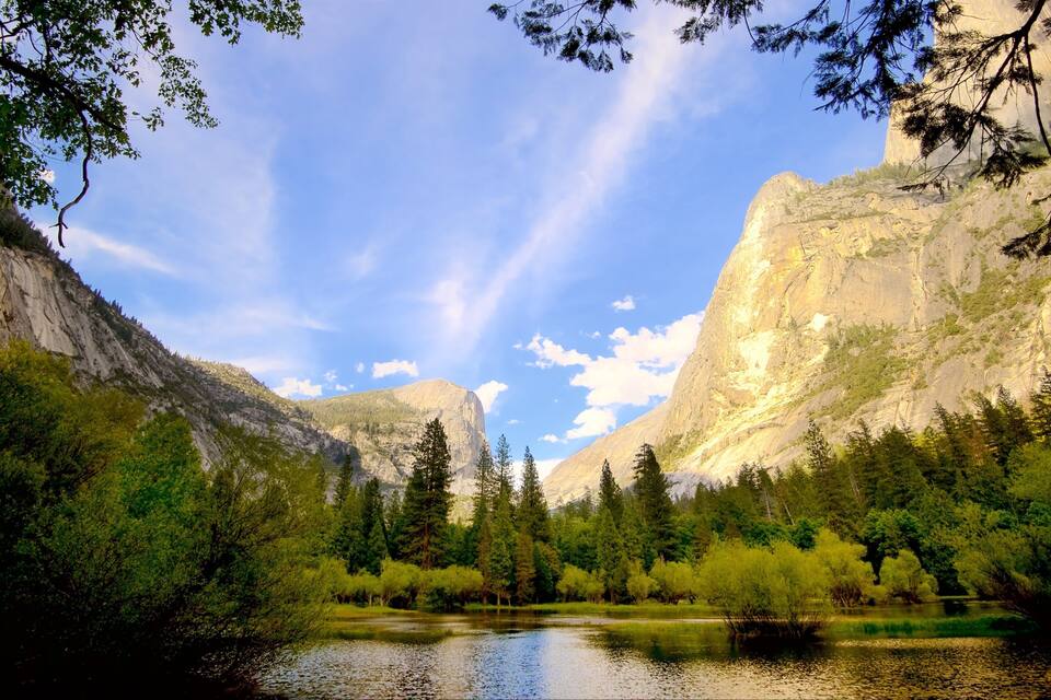 A serene lake surrounded by dense forest and towering mountains.