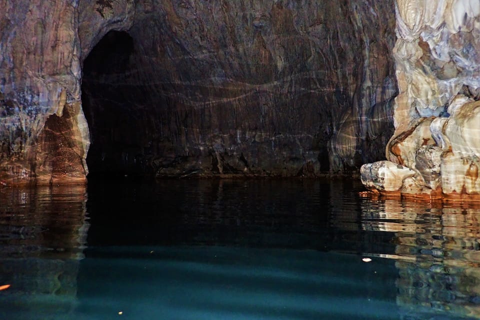 A cave with a water pool and a narrow passageway.