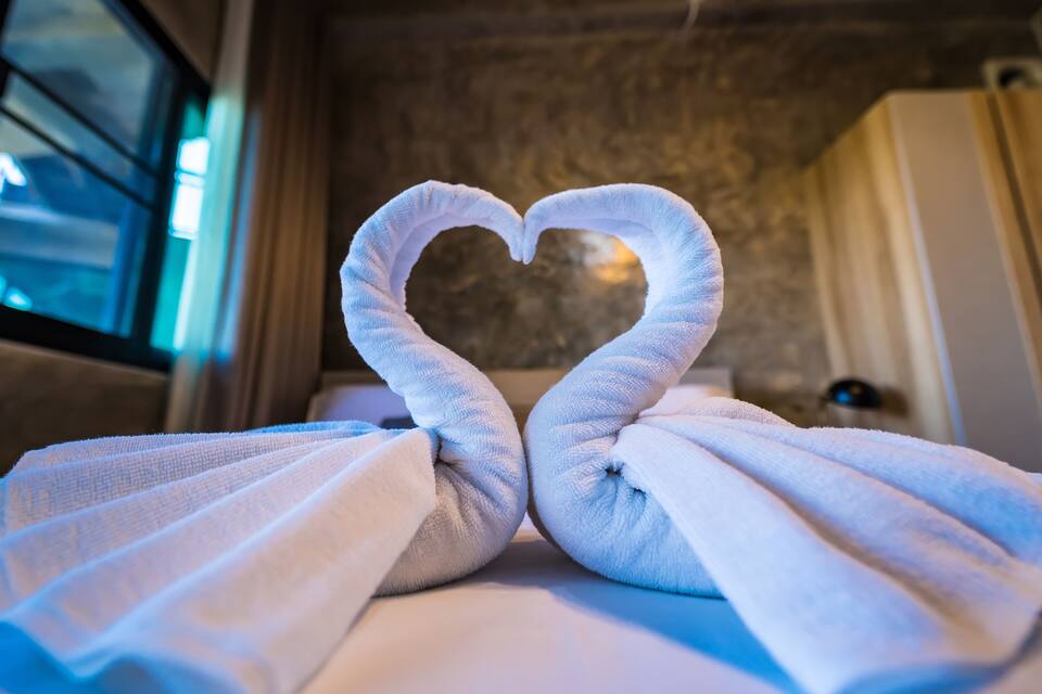 A towel arranged in a heart shape on a bed.