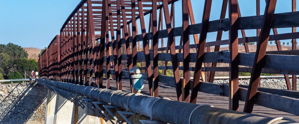 Distinctive wooden trestle footbridge used by bicyclists, runners and dog walkers to cross over the Santa Ana River. Huntington Beach, CA.