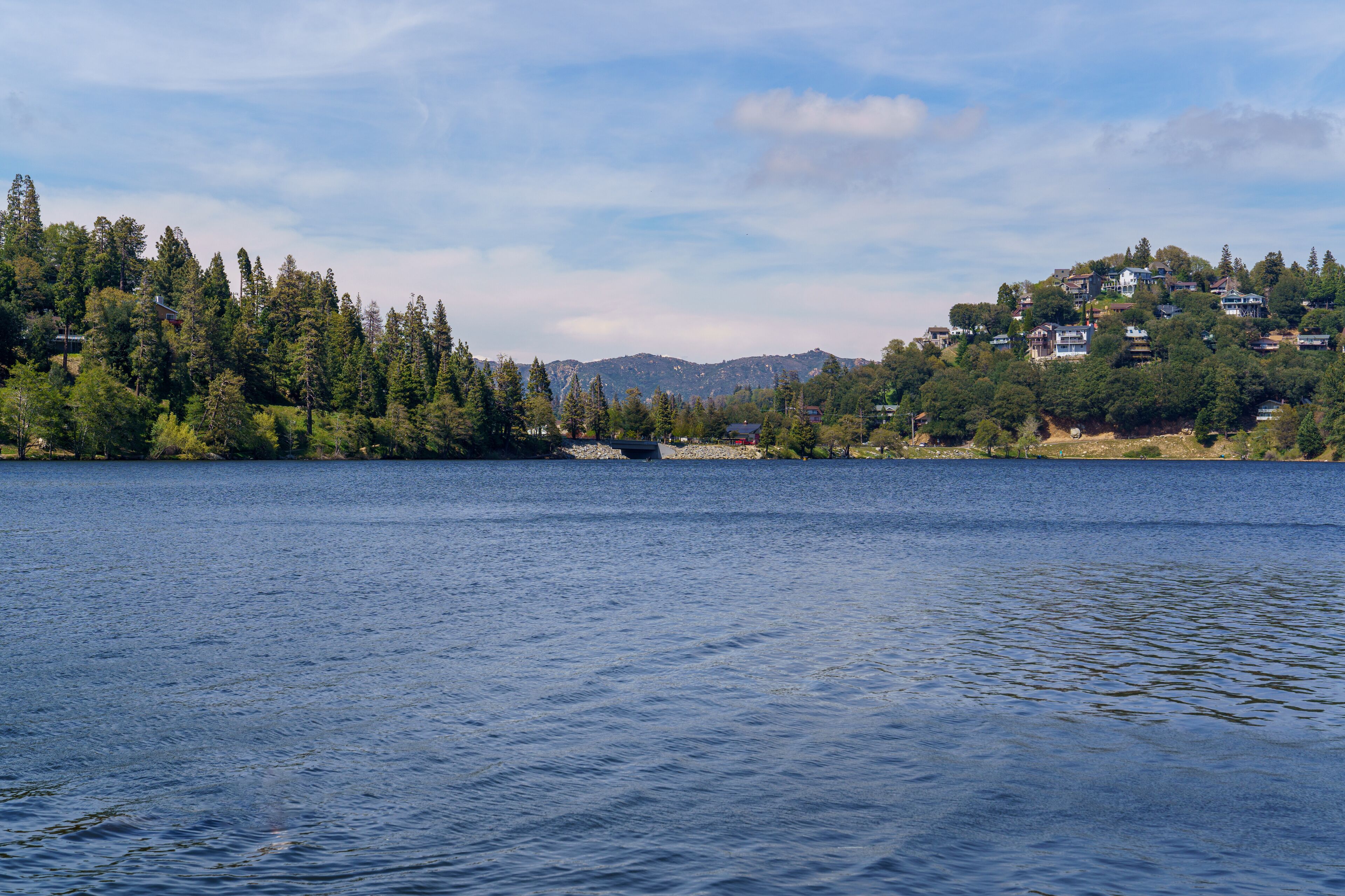 View of the water, shoreline, and mountains at Lake Gregory Regional Park in Crestline, California