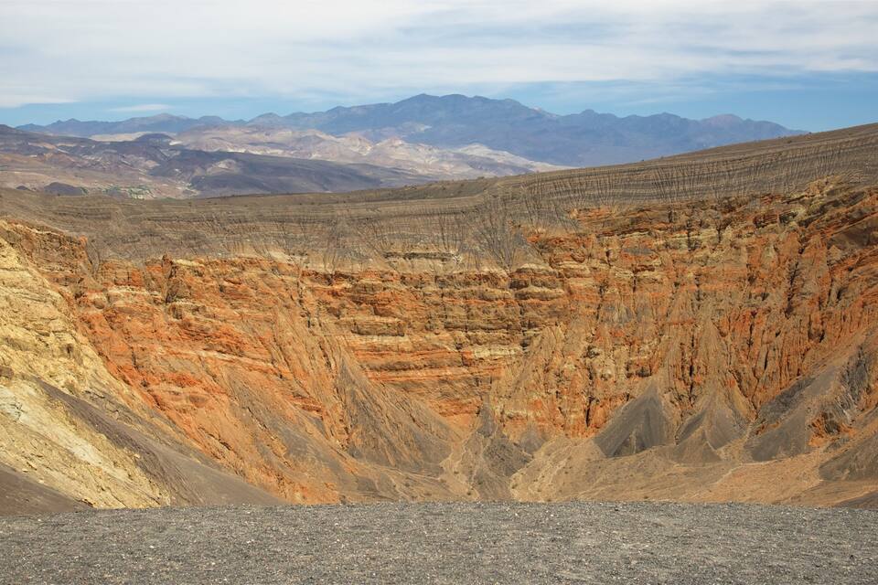 A rugged canyon with layered rock formations and distant mountains.