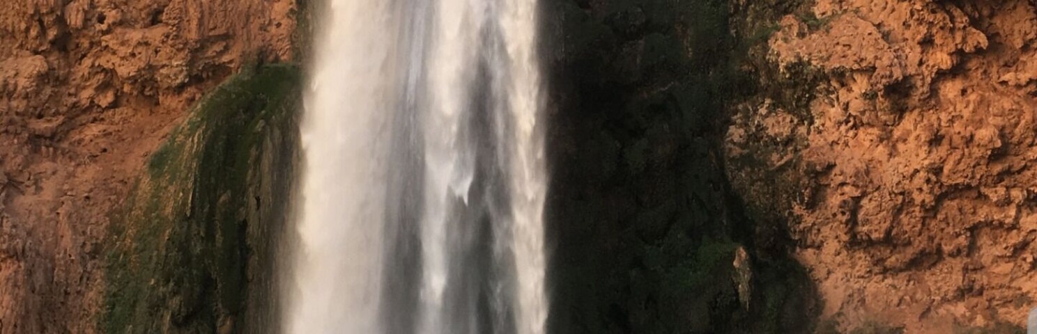 Una cascada se precipita por un acantilado rocoso mientras una persona toma una fotografía.