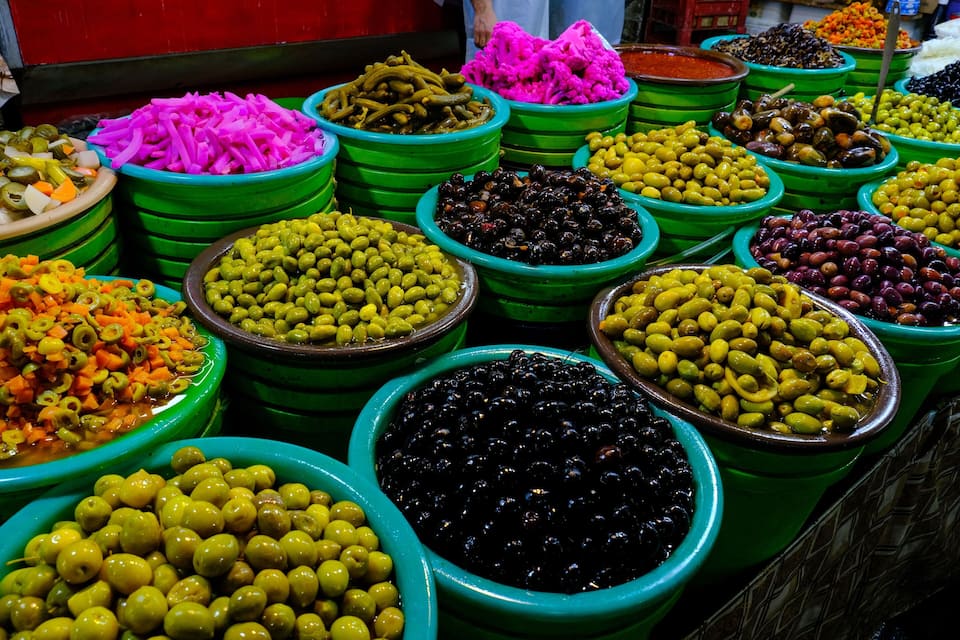 A variety of olives in different colors and types displayed in green bowls.