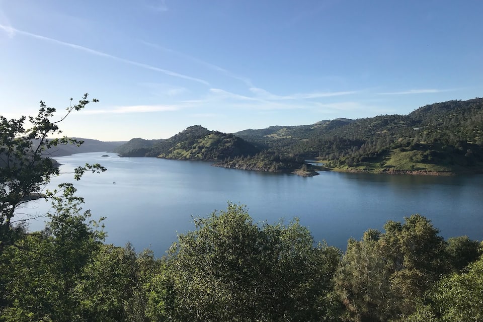 A calm lake surrounded by lush green hills and trees.