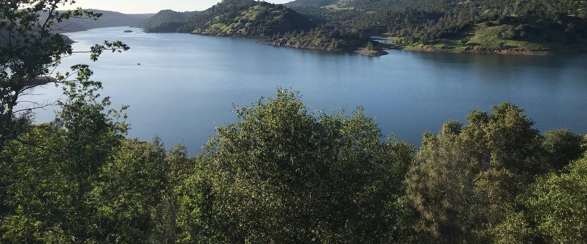 A calm lake surrounded by lush green hills and trees.