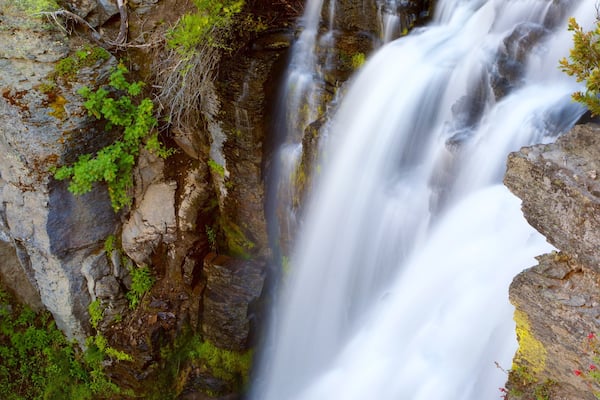 A waterfall cascading over rocky terrain with moss and small plants growing on the rocks.