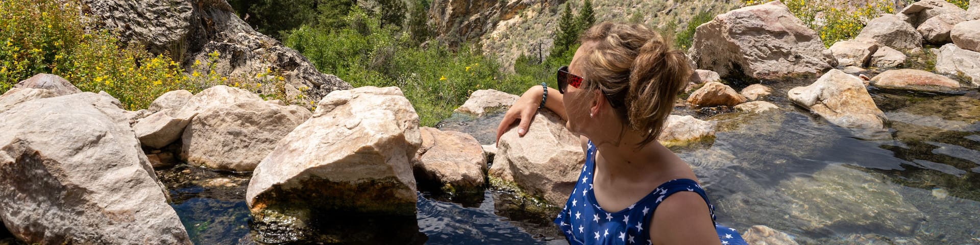 Cute adult woman wearing an American flag swimsut soaks and enjoys the Goldbug Hot Springs in the Salmon Challis National Forest of Idaho