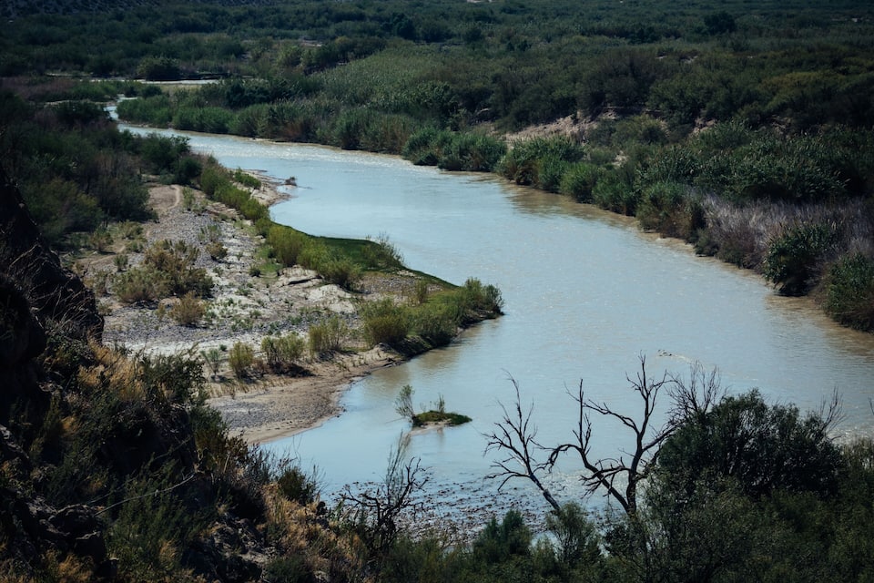 A river winding through a dry, rocky landscape with sparse vegetation.