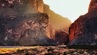 A canyon with steep rock walls and a river at its base.