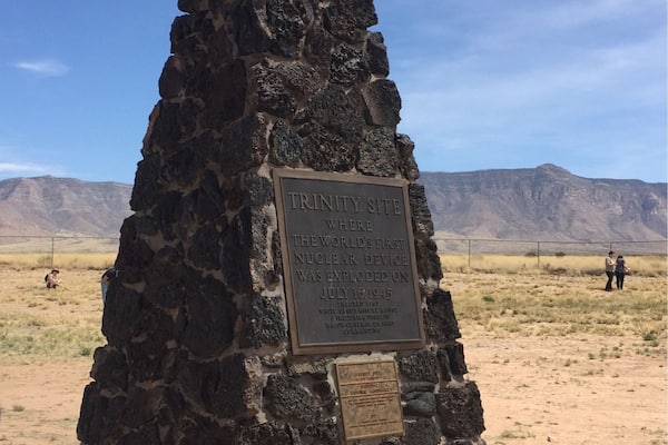 Un monument de pierre surmonté d’une plaque, situé dans un paysage désertique.