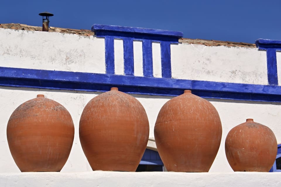 Terracotta pots against a white wall with blue trim.