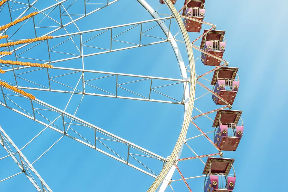 A Ferris wheel with multiple cabins against a clear blue sky.