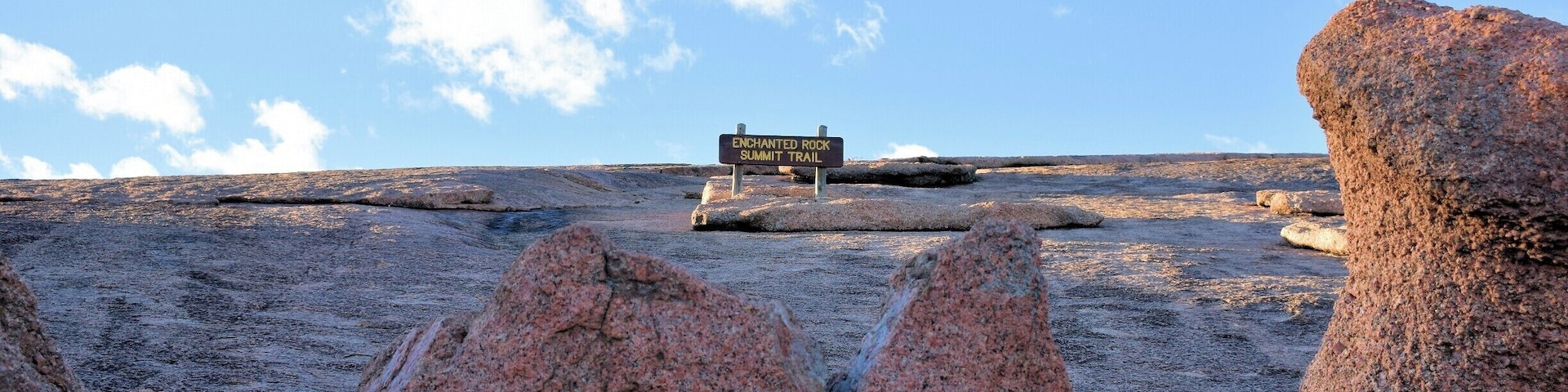 Paisaje rocoso con un cartel que indica "Enchanted Rock Summit Trail".