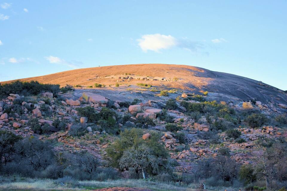 A rocky hill with sparse vegetation and a clear sky.