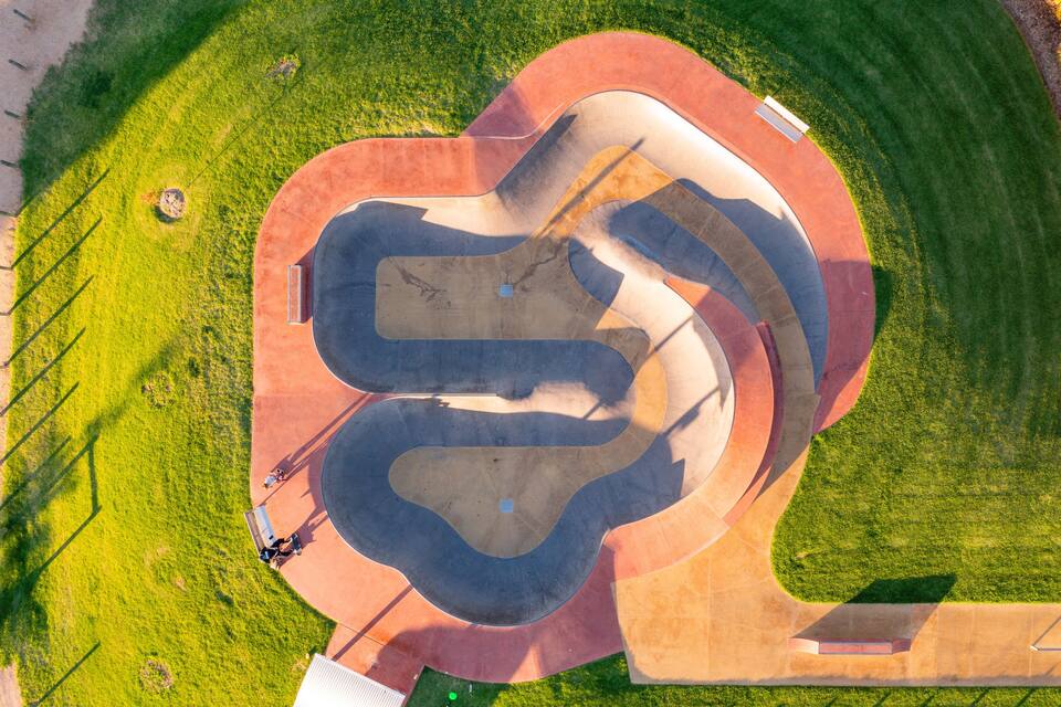 An aerial view of a park with a winding path and a central pond.