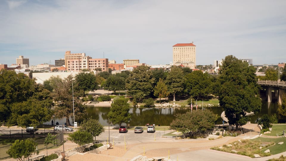 A cityscape with a large building, a bridge, and a lake.