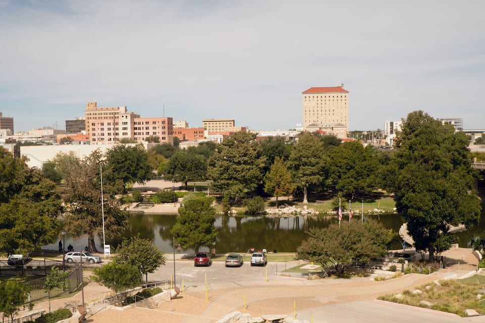 Une vue urbaine avec un grand immeuble, un pont et un lac.