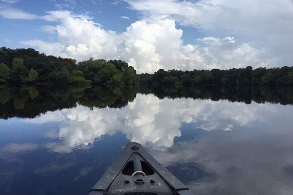 Un lago tranquilo que refleja claramente el cielo y los árboles.