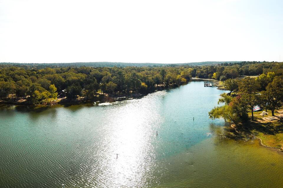 A river winding through a densely wooded area with a boat docked on the right side.
