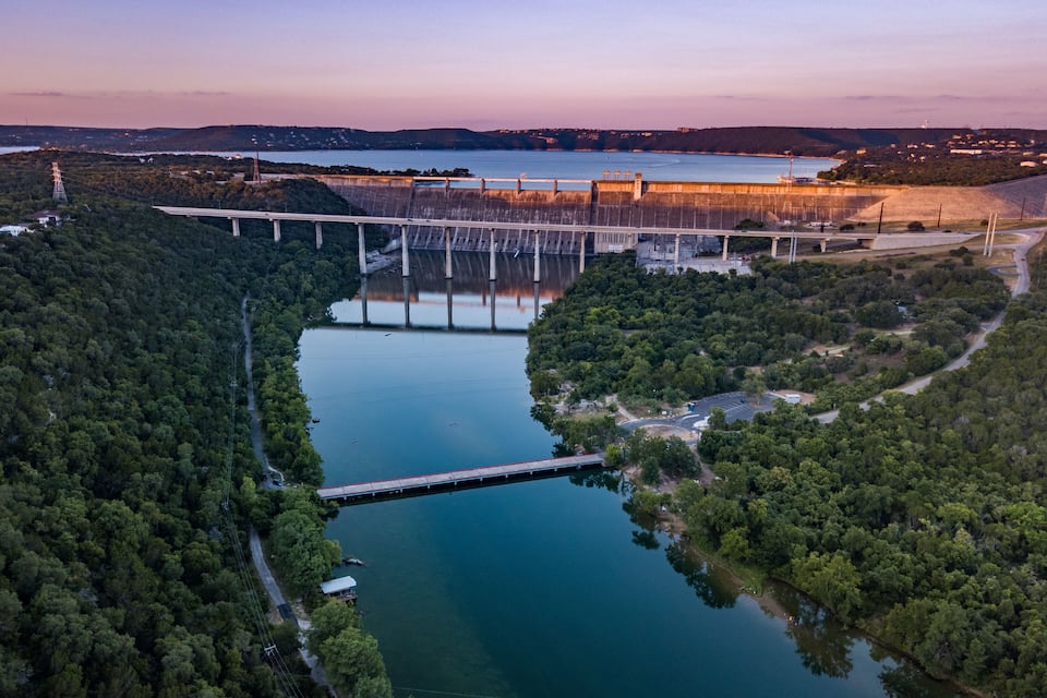 A dam with a bridge, a river, and surrounding forest.
