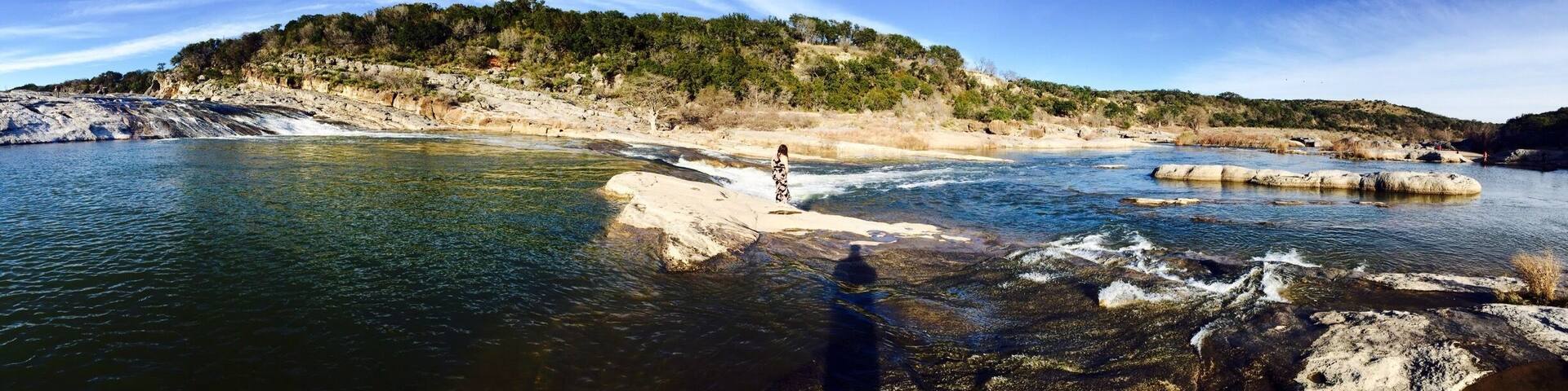 A river flowing through a rocky landscape with a person standing on a rock in the water.