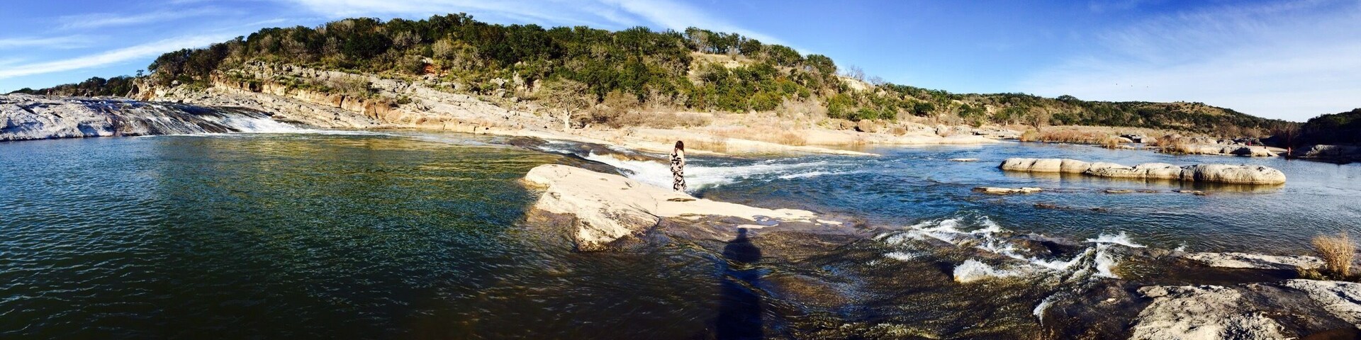 A river flowing through a rocky landscape with a person standing on a rock in the water.