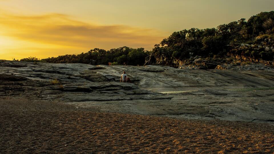 A rocky landscape with a person sitting on a rock.