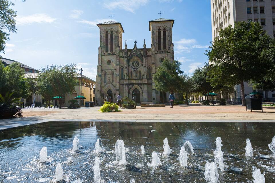 A historic cathedral with twin towers, a central rose window, and a fountain in the foreground.