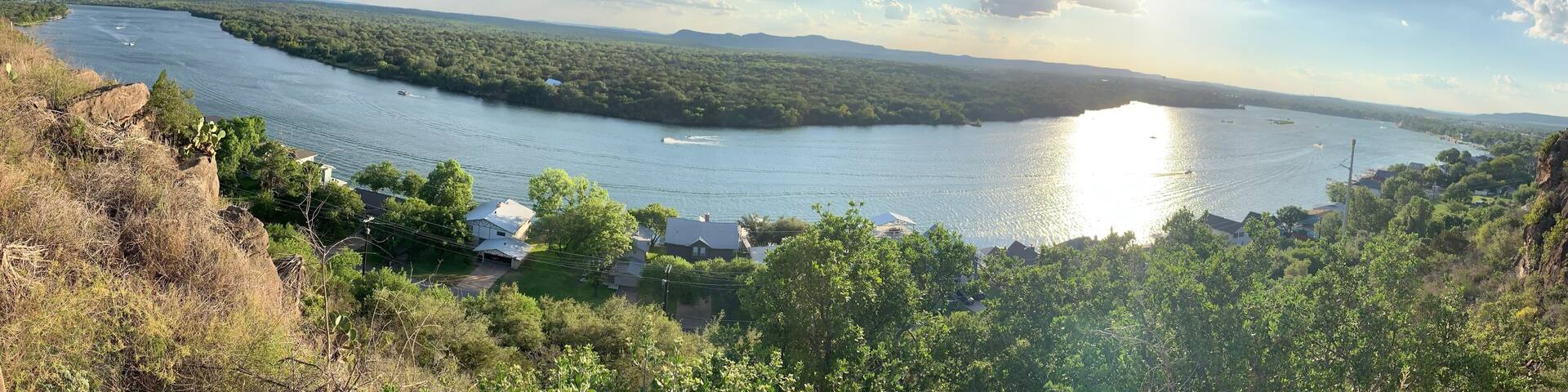 A river, river, boats, houses, trees, and a distant mountain range.