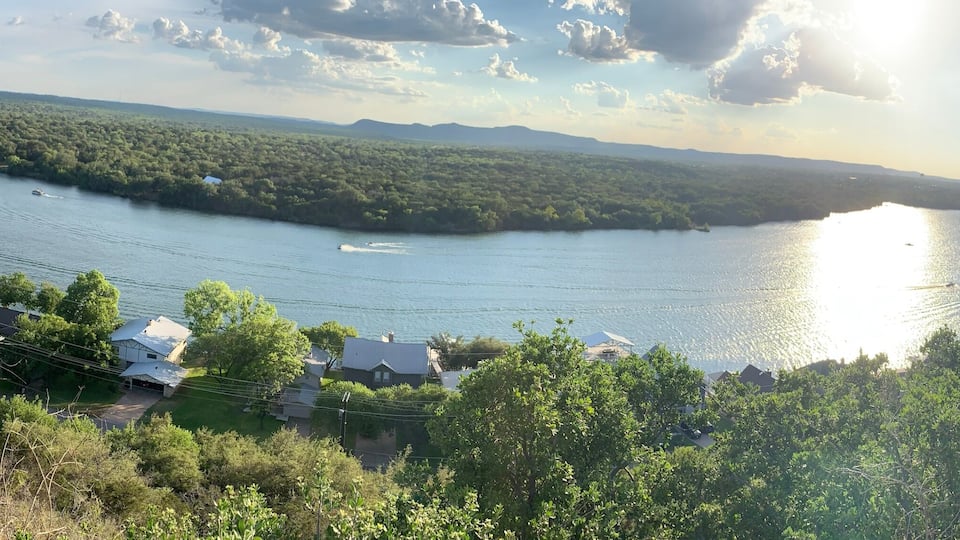 A river, river, boats, houses, trees, and a distant mountain range.