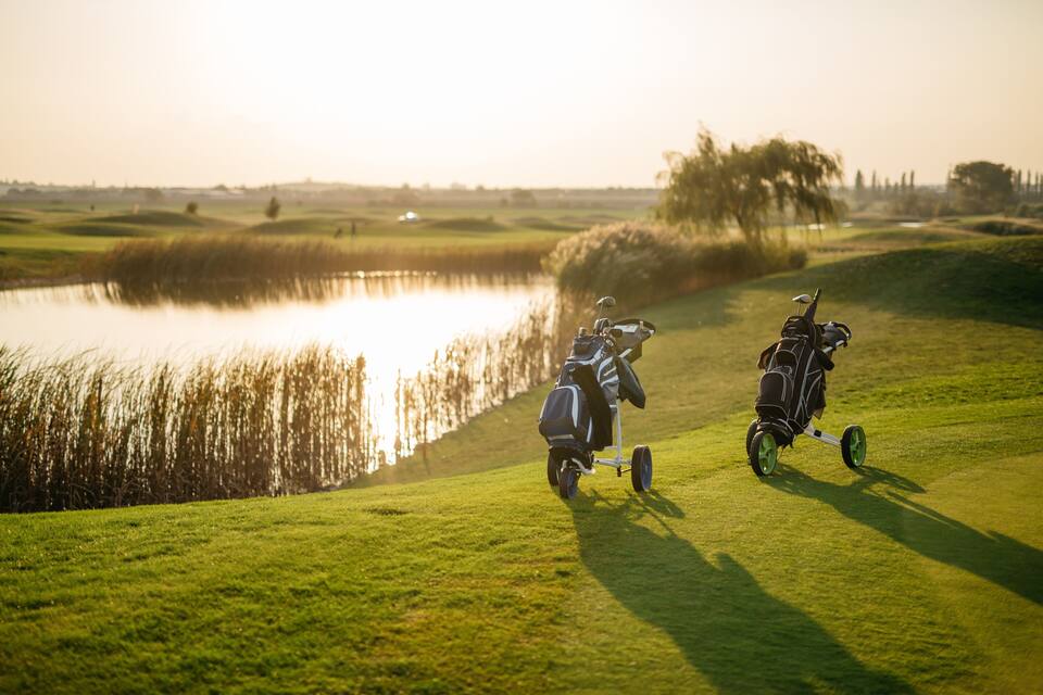 Un campo de golf con dos carritos de golf y un estanque.
